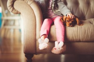 small child sits with dog on a sofa
